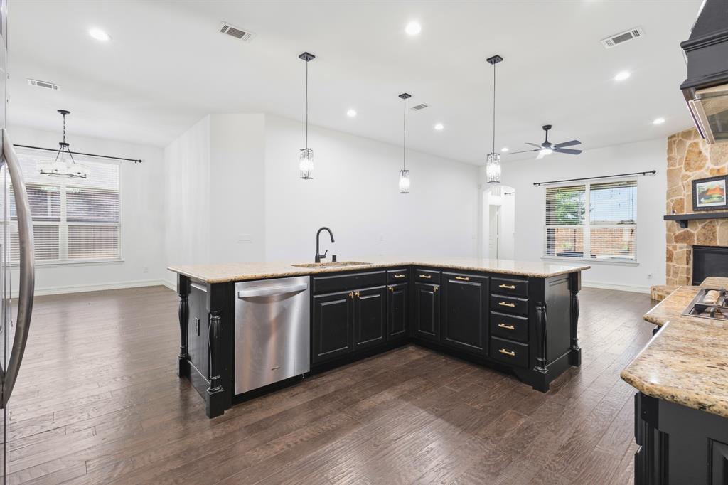 1995 Verde Court Allen, TX 75013 - Photo 17 of 30 L-shaped kitchen island featuring a stainless steel dishwasher, black cabinetry with gold-tone hardware, and a light-toned countertop
