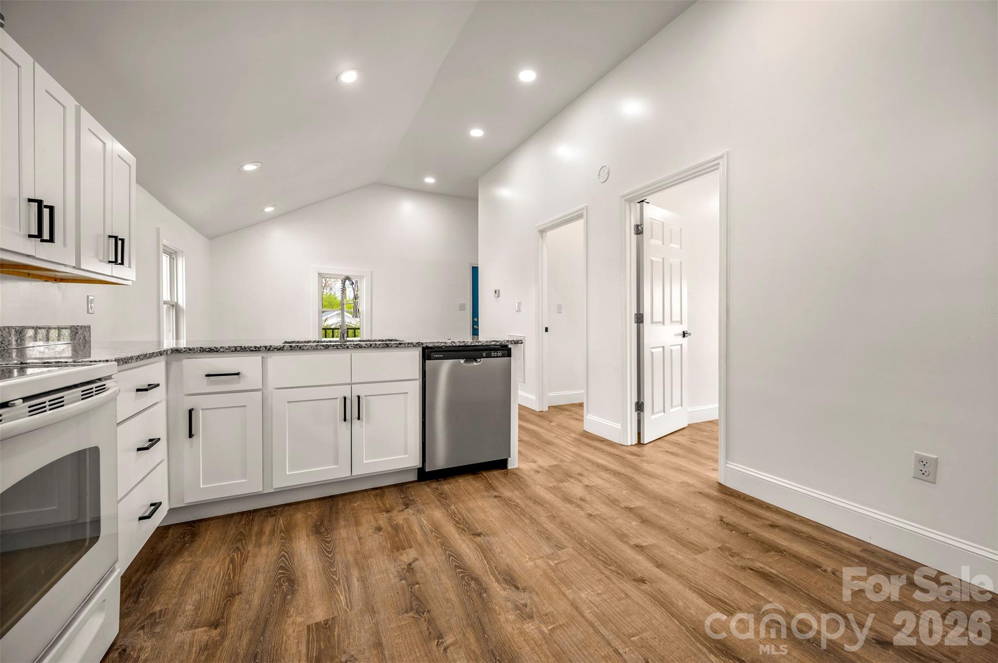 162 Miller Street Spindale, NC 28160 - Photo 7 of 27 a large white kitchen with a sink dishwasher a stove and white cabinets with wooden floor