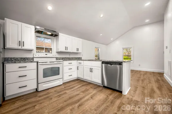 a kitchen with granite countertop white cabinets and white appliances