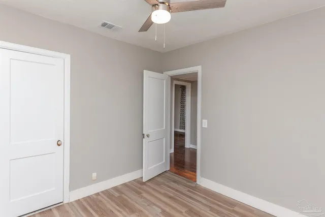 an empty room with wooden floor and fan