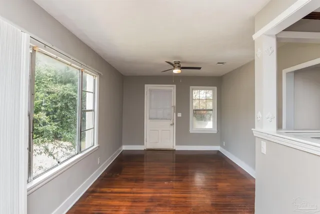 a view of an empty room with wooden floor and a window