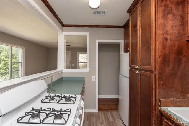 a view of a hallway with wooden floor and a bathroom