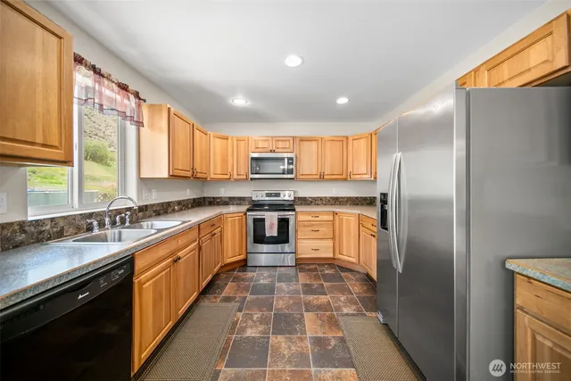a kitchen with stainless steel appliances granite countertop a sink a stove a microwave and wooden cabinets