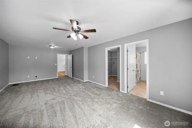 an empty room with windows and ceiling fan