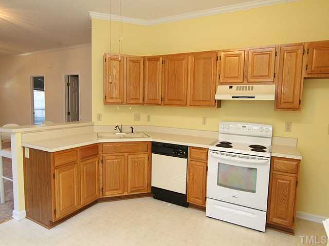 4475 Still Pines Drive Raleigh, NC 27613 - Photo 5 of 12 a kitchen with stainless steel appliances granite countertop a stove a sink and a refrigerator with wooden cabinets
