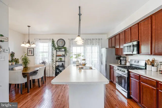 a kitchen with stainless steel appliances a dining table chairs stove refrigerator and cabinets