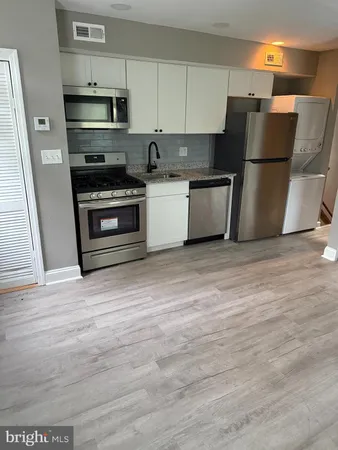 a kitchen with stainless steel appliances a refrigerator stove and white cabinets
