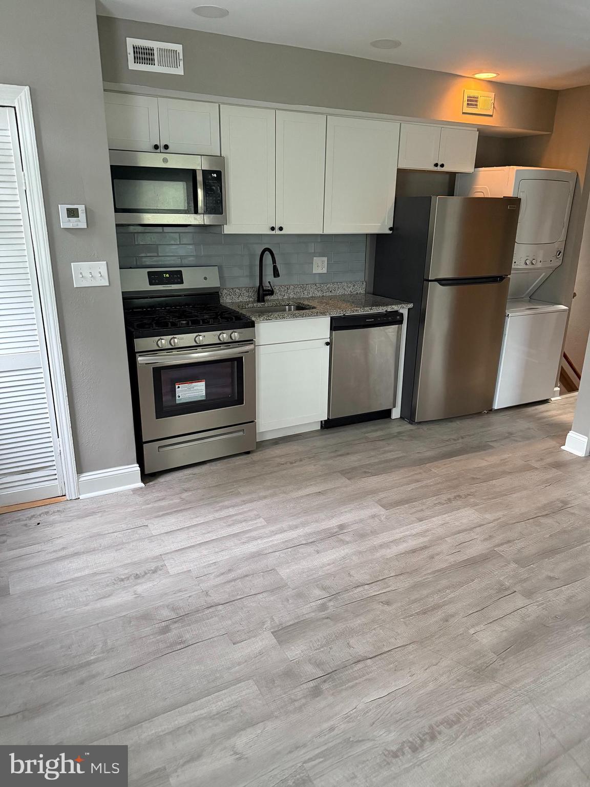 a kitchen with stainless steel appliances a refrigerator stove and white cabinets