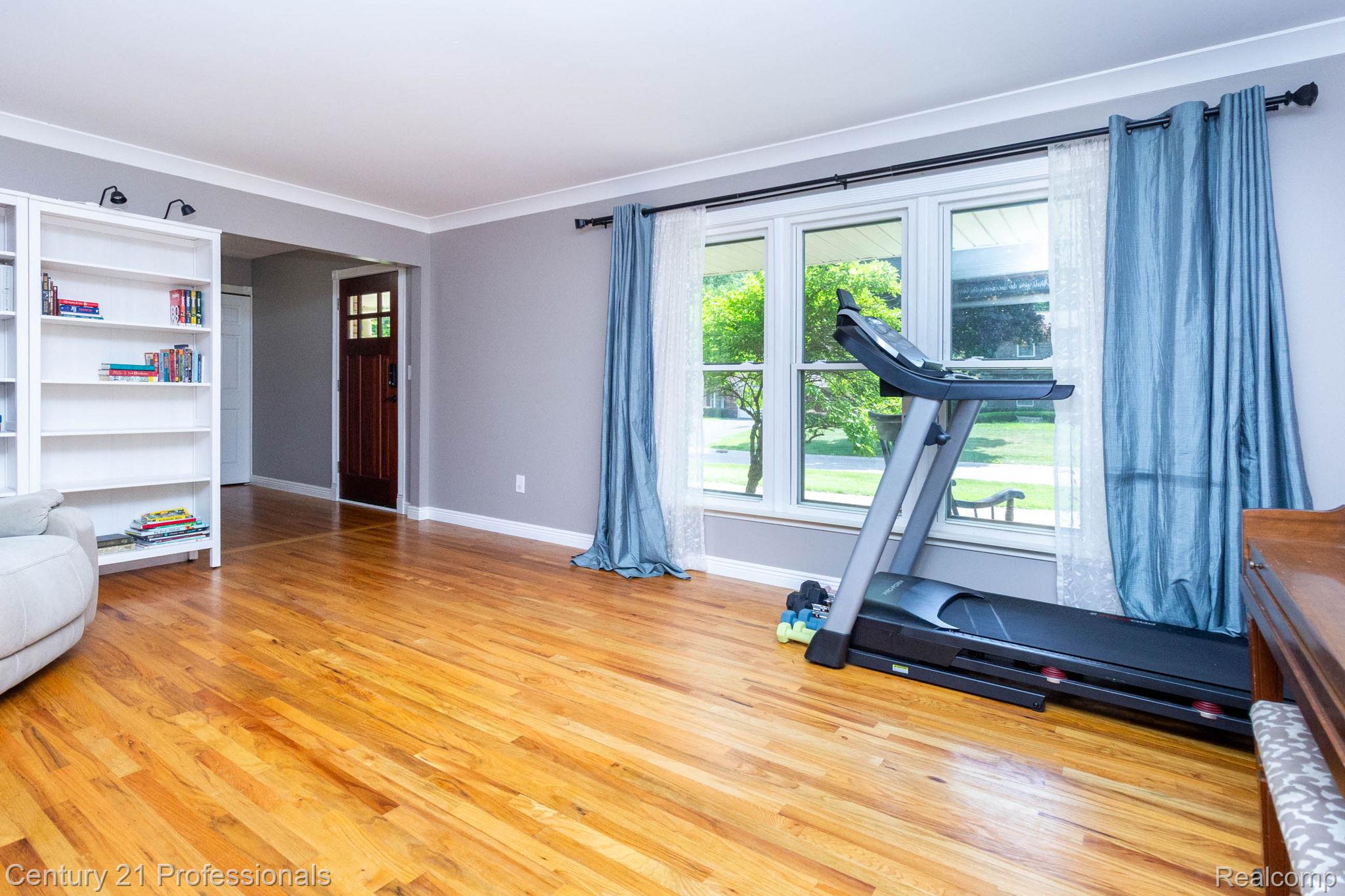 671 Bridgestone Drive Rochester, MI 48309 - Photo 8 of 50 Hardwood flooring throughout the room, large window offering natural light, built-in white shelving, and crown molding