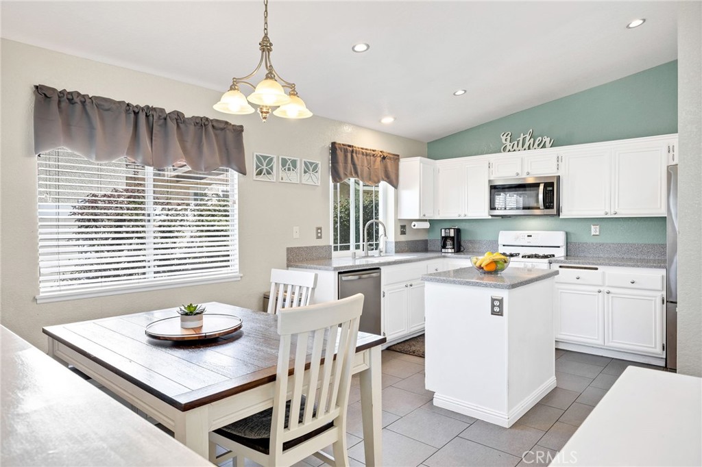 3147 Wimbledon Way Hemet, CA 92545 - Photo 16 of 41 a kitchen with a sink a stove a kitchen island and chairs
