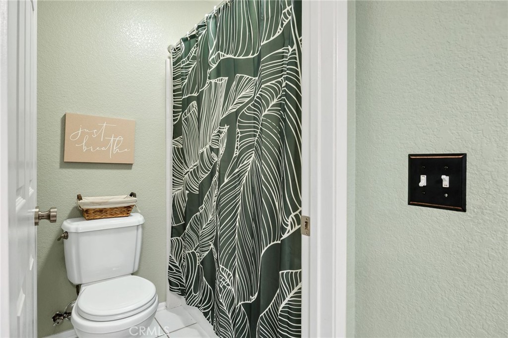 3147 Wimbledon Way Hemet, CA 92545 - Photo 28 of 41 a bathroom with a toilet and a shower curtain