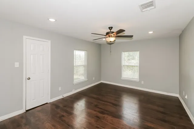 a view of an empty room with a window and wooden floor
