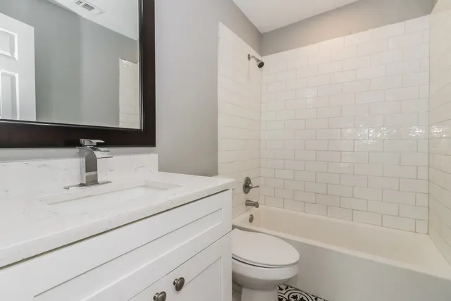 a bathroom with a bathtub shower sink vanity mirror and toilet
