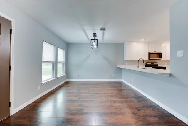 a view of a kitchen with a sink dishwasher wooden floor and a window