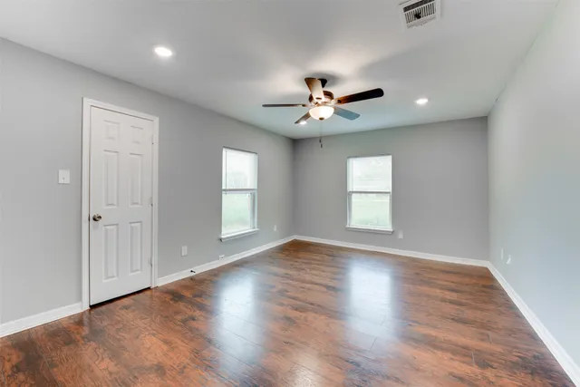 a view of an empty room with a window and wooden floor