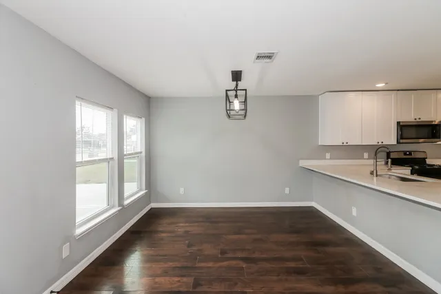 a view of a kitchen with wooden floor and electronic appliances