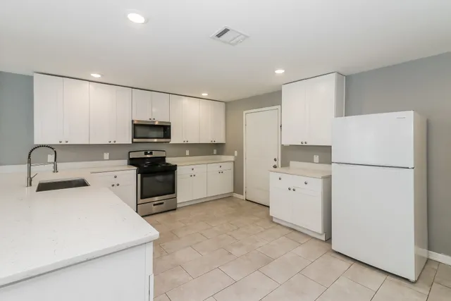 a kitchen with white cabinets and white appliances