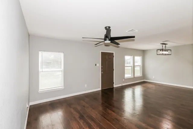 a view of empty room with wooden floor and fan