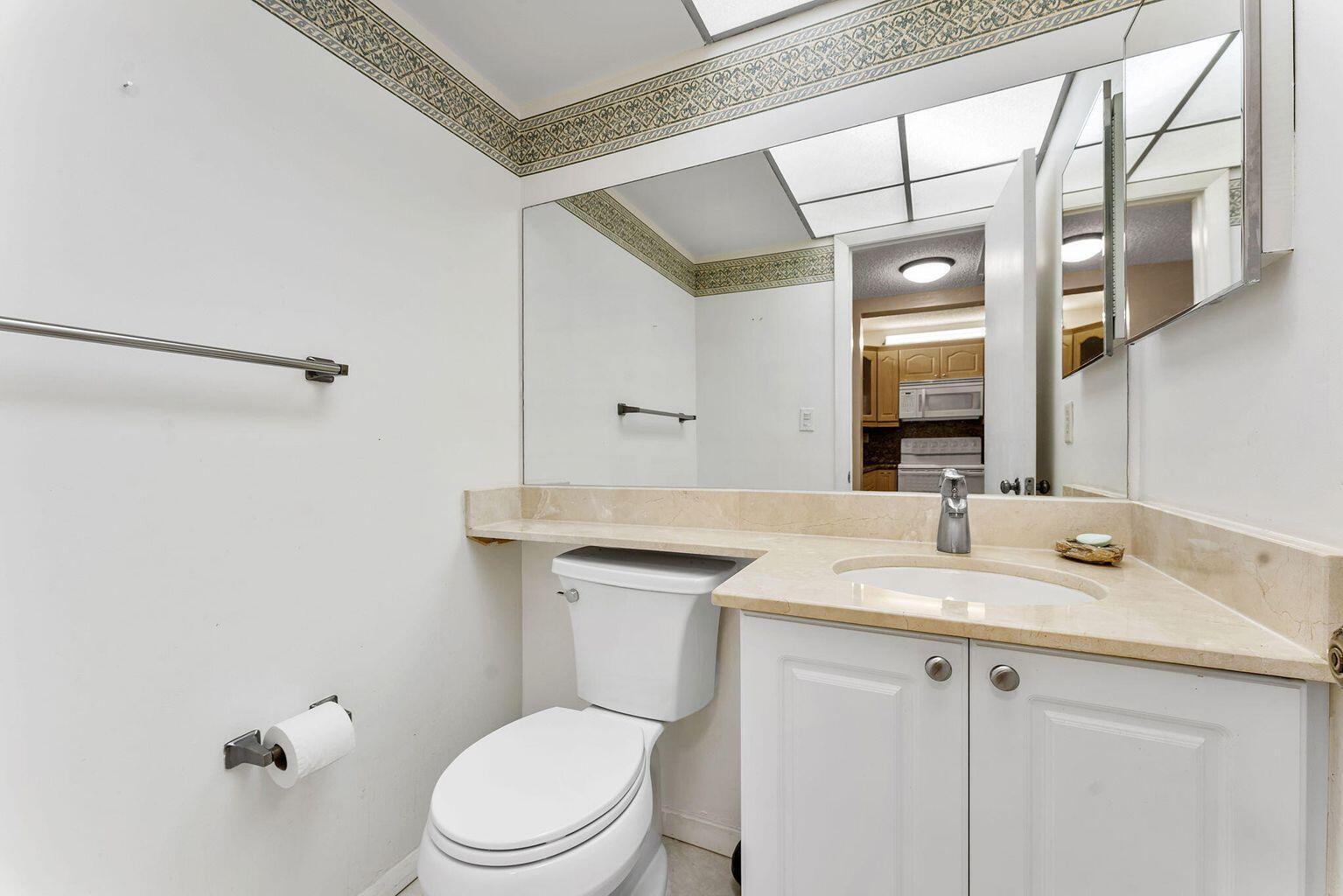 9440 Southwest 8th Street, Unit 318 Boca Raton, FL 33428 - Photo 9 of 11 a bathroom with a sink a toilet and a mirror