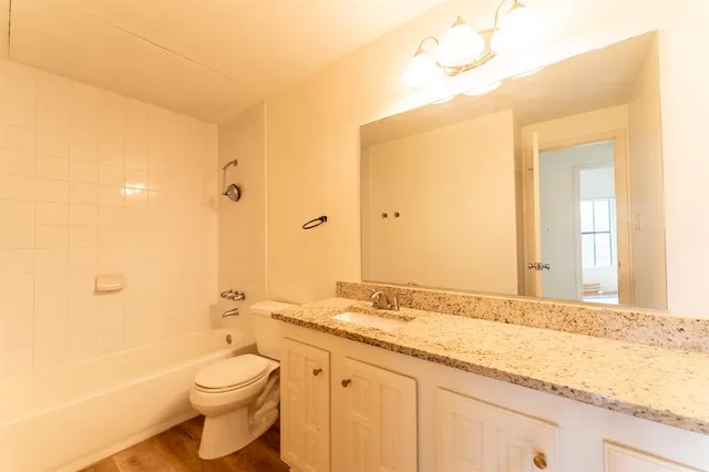 a bathroom with a granite countertop sink a toilet and shower