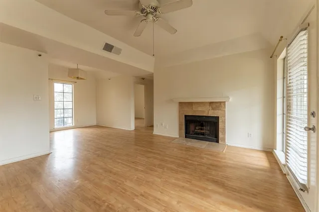 a view of an empty room with wooden floor fireplace and a window
