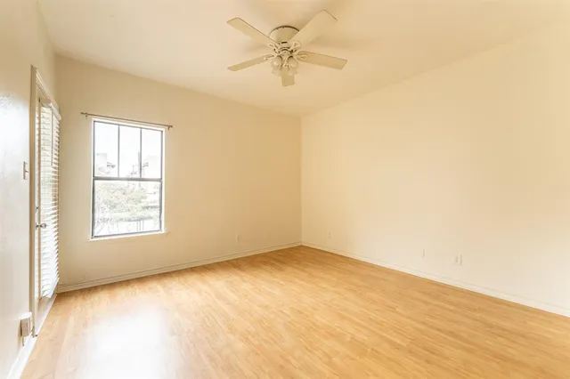 an empty room with a window and a ceiling fan