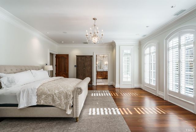 a spacious bedroom with a large bed and a chandelier