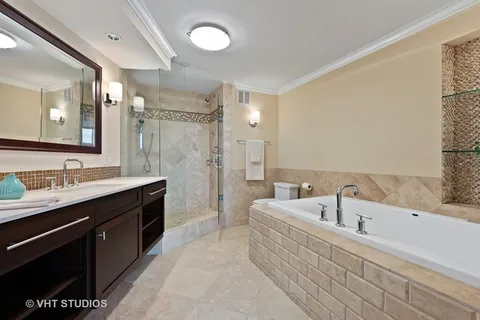 a bathroom with a tub a sink double vanity and a mirror