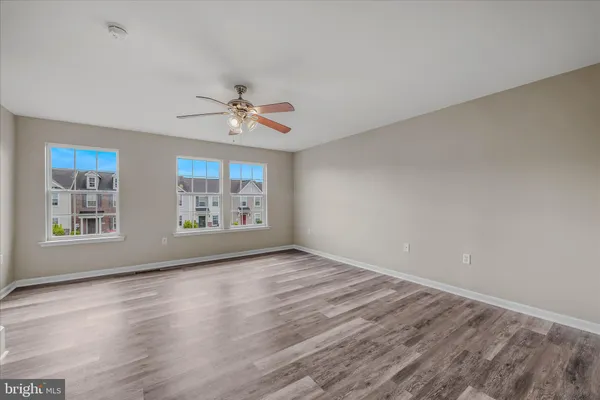 a view of empty room with wooden floor and ceiling fan
