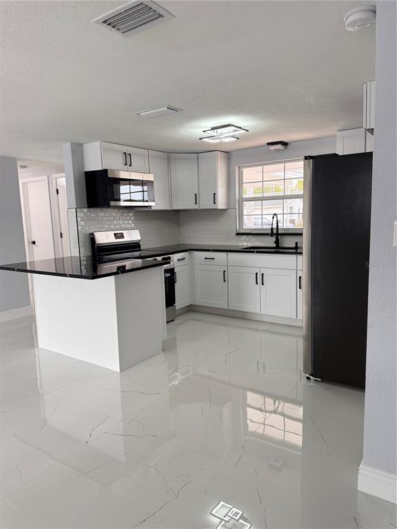 10433 Laburnum Drive Port Richey, FL 34668 - Photo 19 of 26 a large kitchen with stainless steel appliances granite countertop a stove a sink and a refrigerator