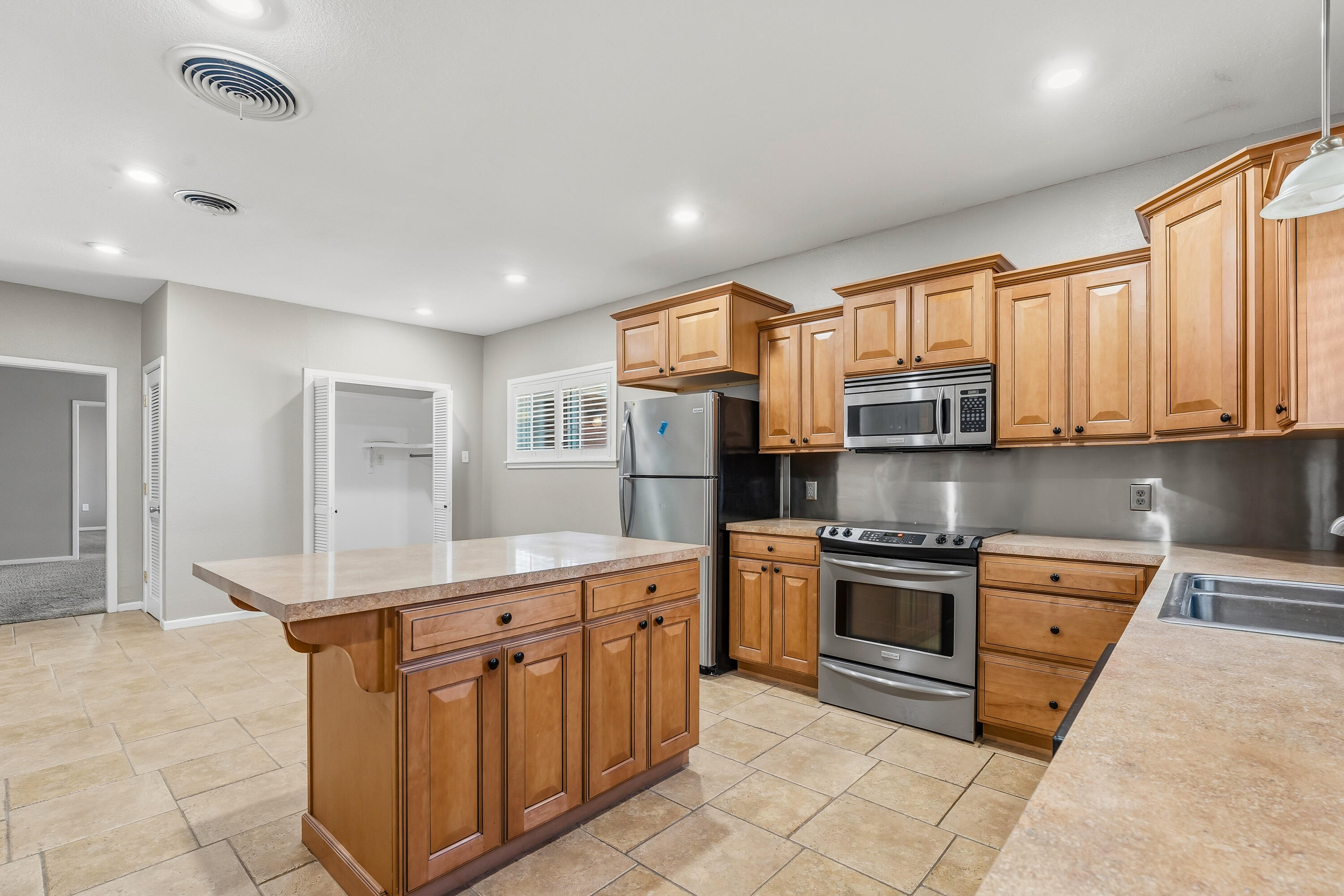 4831 10th Street Lubbock, TX 79416 - Photo 11 of 25 a kitchen with stainless steel appliances granite countertop a stove top oven a sink dishwasher and a refrigerator with wooden cabinets