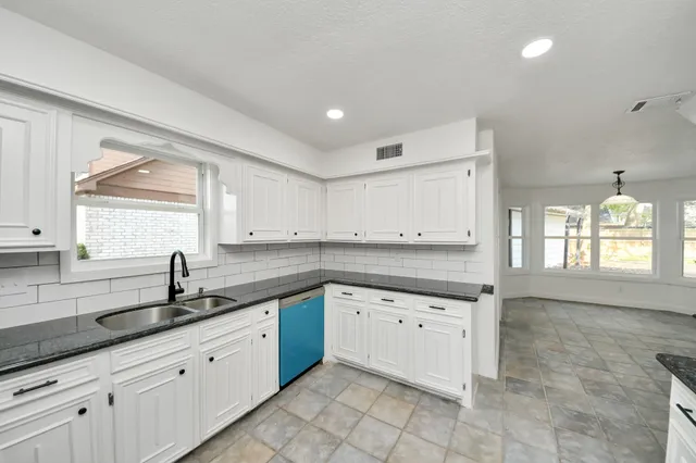 a kitchen with stainless steel appliances granite countertop a refrigerator sink and white cabinets