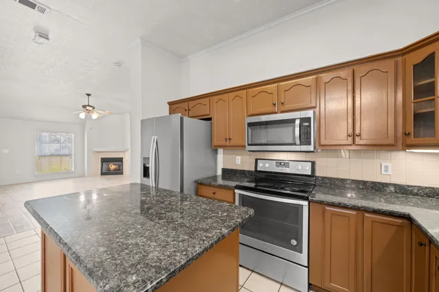 a kitchen with stainless steel appliances granite countertop a refrigerator a sink dishwasher a stove with white cabinets