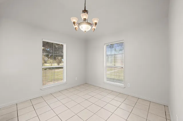 an empty room with chandelier fan and view of an empty room