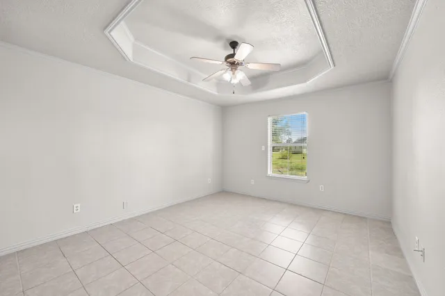 an empty room with chandelier fan and windows