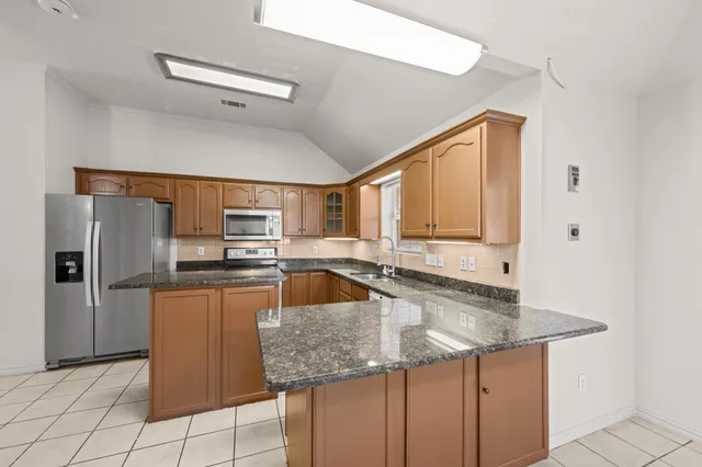 a kitchen with stainless steel appliances granite countertop a sink a stove and a refrigerator