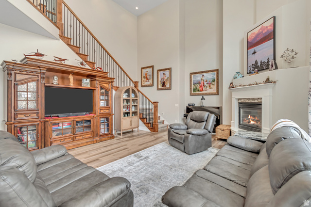 2543 East 700 South Springville, UT 84663 - Photo 24 of 73 Living area with light wood finished floors, a high ceiling, and a glass covered fireplace