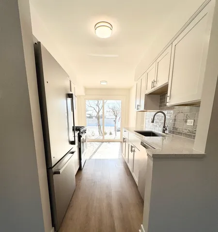 a kitchen with sink a refrigerator and wooden floor