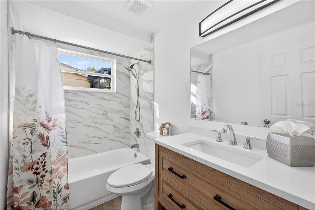 4928 Amherst Court New Port Richey, FL 34652 - Photo 14 of 50 a bathroom with a sink a toilet a mirror a bathtub and shower