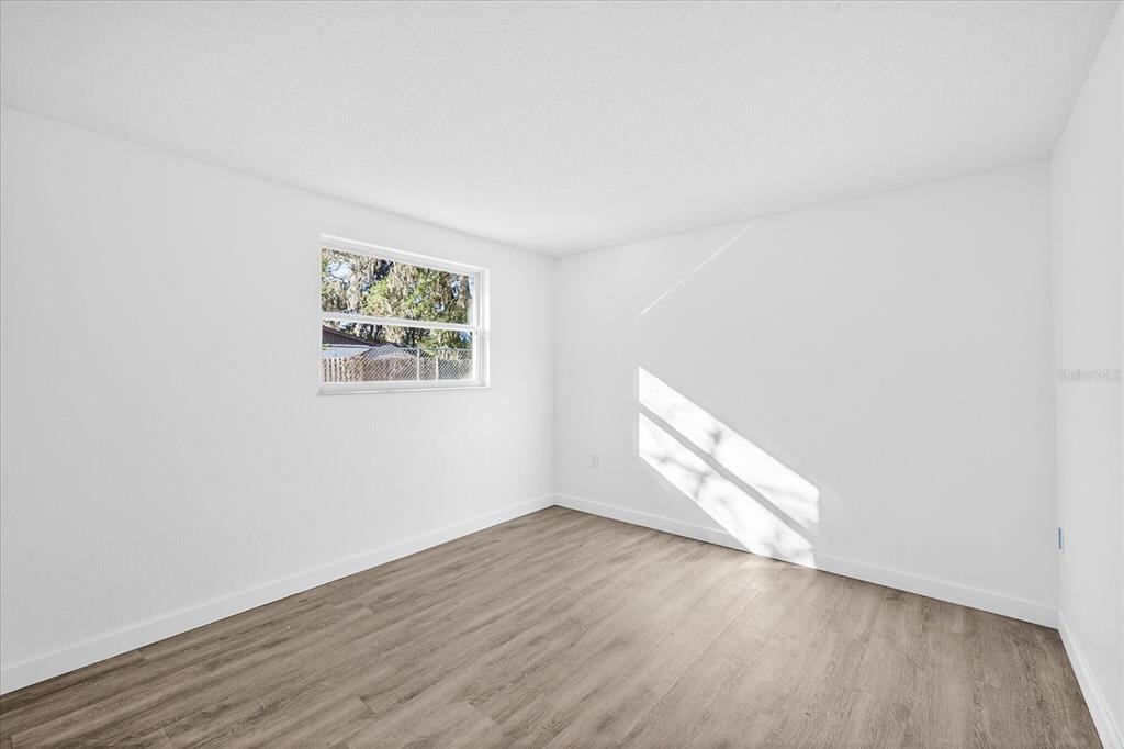 4928 Amherst Court New Port Richey, FL 34652 - Photo 32 of 50 an empty room with wooden floor and windows