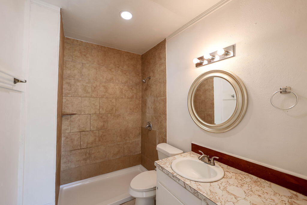 532 54th Street Lubbock, TX 79404 - Photo 10 of 19 a bathroom with a toilet a sink a mirror and a shower