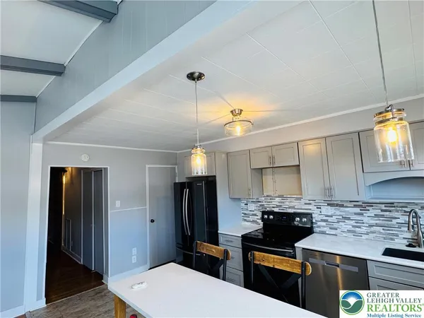 a kitchen with stainless steel appliances kitchen island granite countertop a refrigerator a sink dishwasher and white cabinets with wooden floor