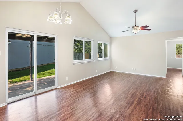 a view of an empty room with a window and wooden floor