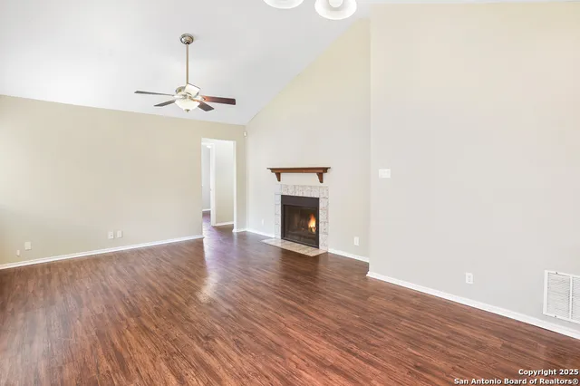 a view of an empty room with wooden floor and a fireplace