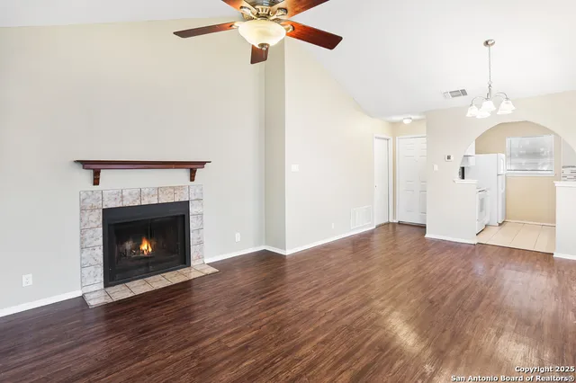 a view of an empty room with wooden floor fireplace and a window