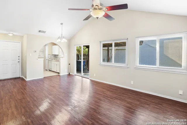 a view of an empty room with a window and wooden floor