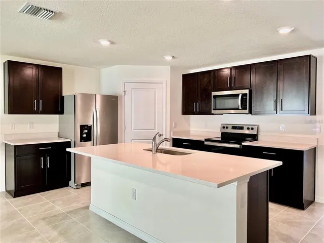 a kitchen with kitchen island a sink stove and refrigerator