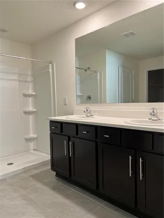 a bathroom with a double vanity sink a toilet and shower