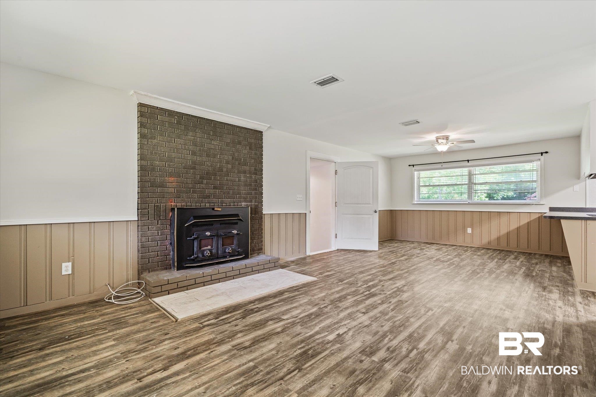 3325 Lacoste Road Mobile, AL 36618 - Photo 8 of 35 Unfurnished living room with brick wall, a brick fireplace, ceiling fan, and hardwood / wood-style floors