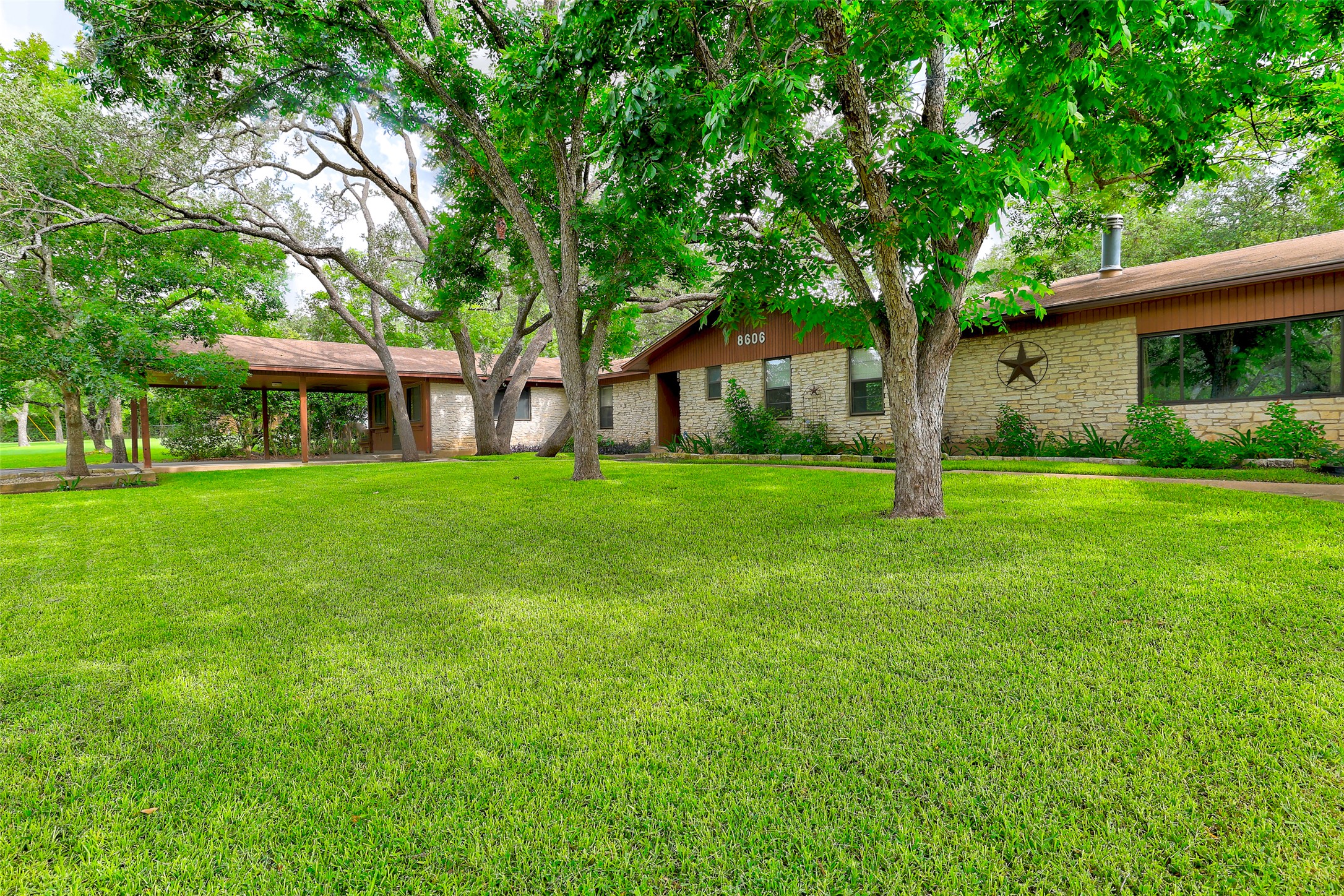 8606 Thunderbird Road, Unit A & B Austin, TX 78736 - Photo 29 of 34 A spacious lawn unfolds before a ranch-style residence featuring stone accents and mature shade trees.